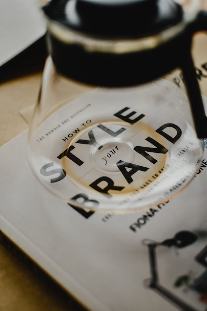 Photo by Eva Bronzini A coffee pot rests atop a book titled 'How to Style Your Brand', capturing the essence of creative branding.
