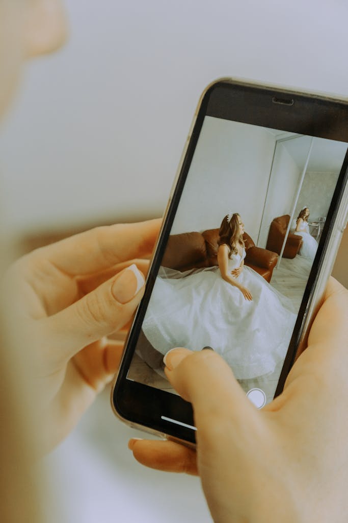 Photo by Marina Abrosimova Bride in white dress photographed with a smartphone, showcasing modern wedding photography.