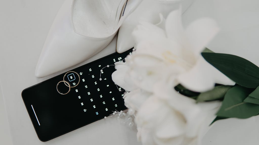 Photo by thecactusena Flat lay of wedding essentials including high heels, rings, and a bouquet on a calendar.